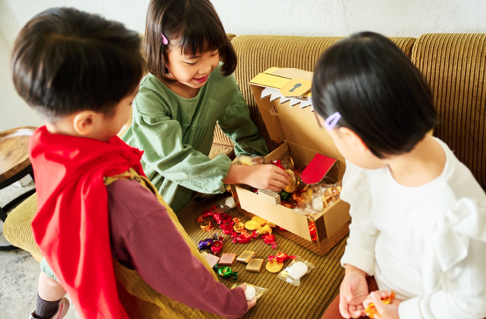 ダンボールでできた手作りの宝箱ピニャータを開けてホームパーティーを楽しむ子ども。