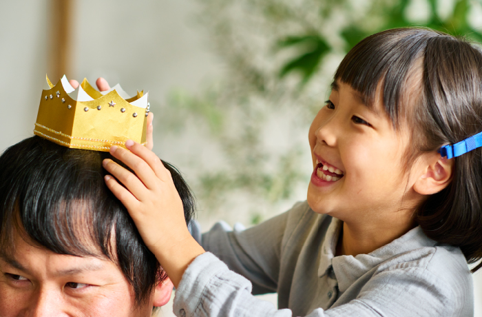 お父さんに紙の王冠をかぶせてあげている子ども。